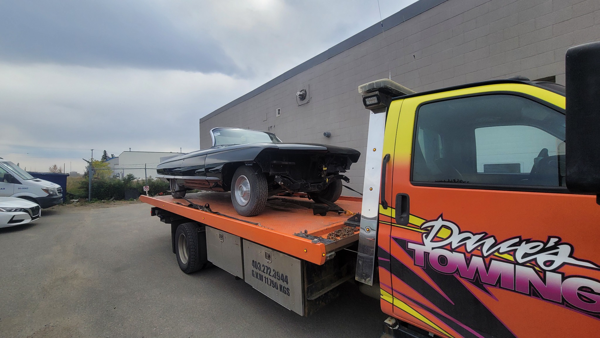 Classic convertible project car being transported on flatbed